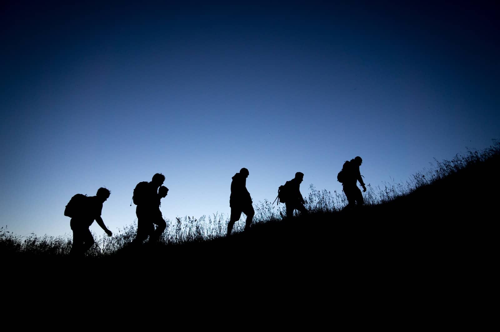 silhouettes de personnes marchant au coucher du soleil